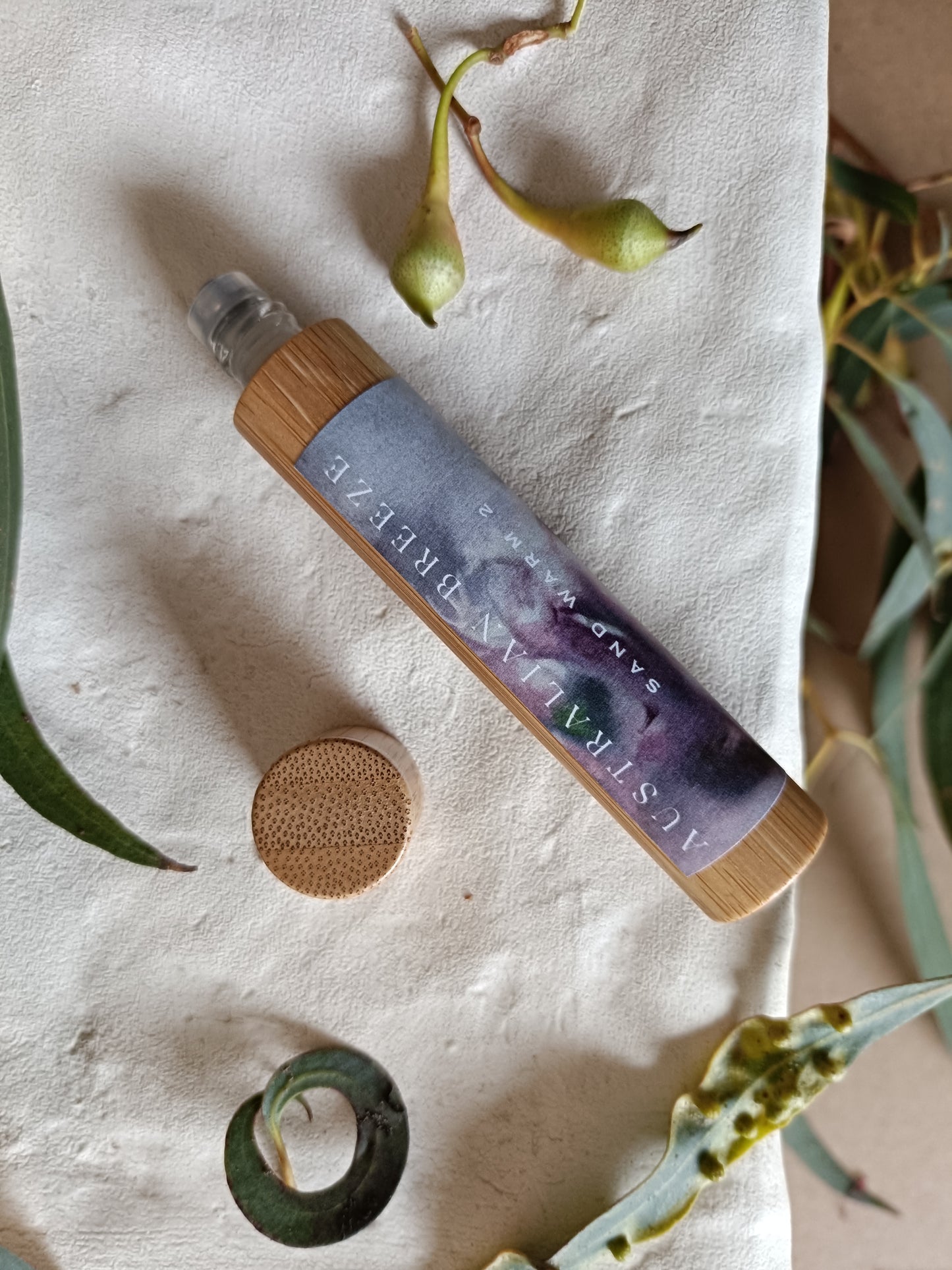 Skincare product with wooden cap on a textured surface with green leaves