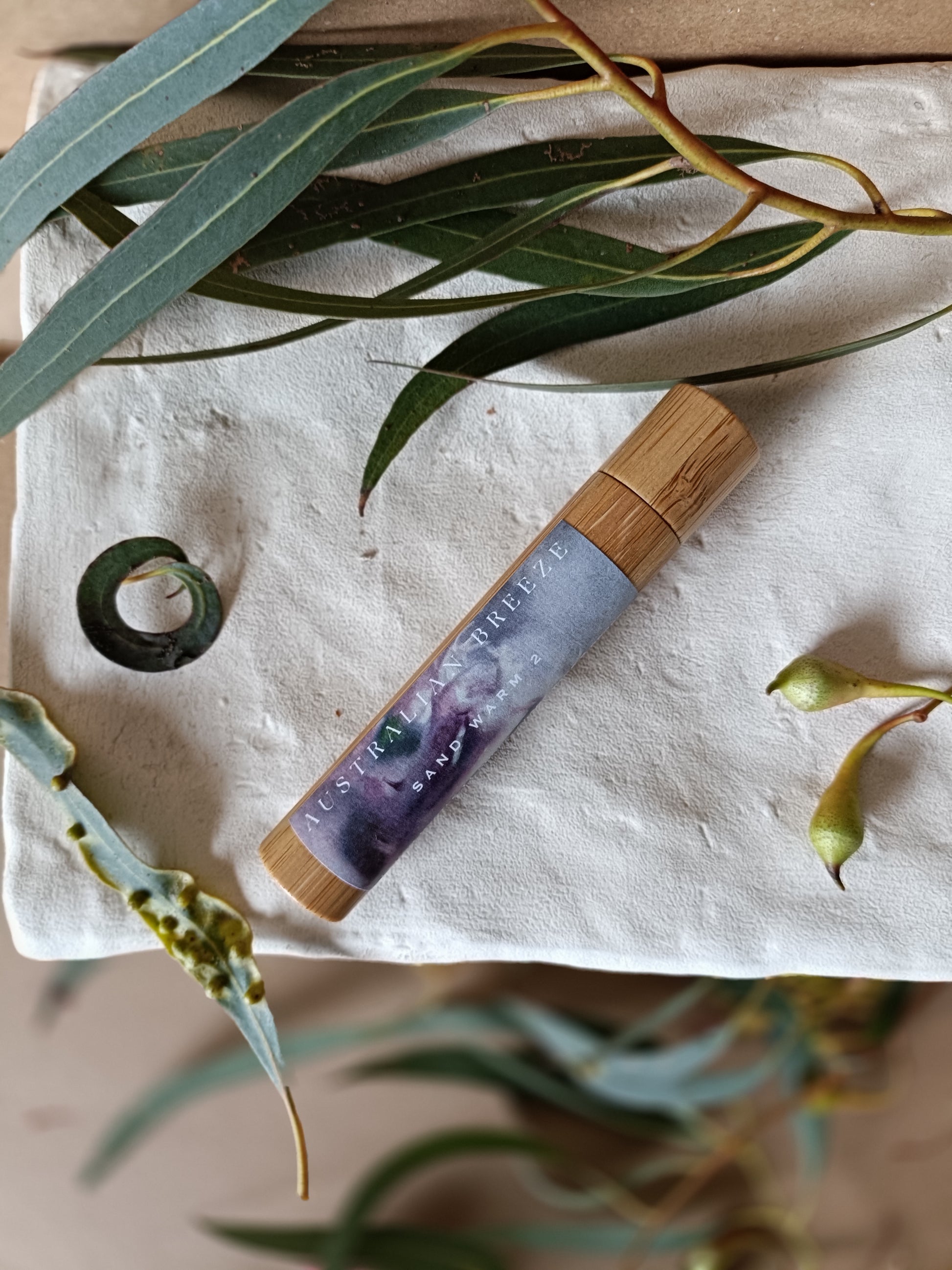 Bamboo roll-on container with a natural design on a textured surface with green leaves.